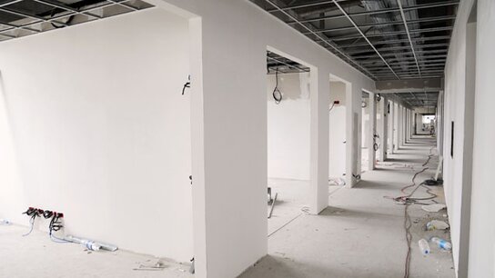 Leere, unvollendete Büroräume mit weißen Wänden und sichtbaren elektrischen Installationen im Boden.