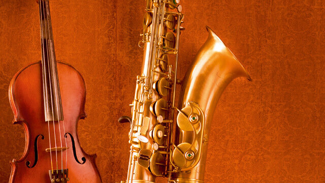 Violine und Saxophon vor einem warmen, strukturierten Hintergrund in Goldtönen.