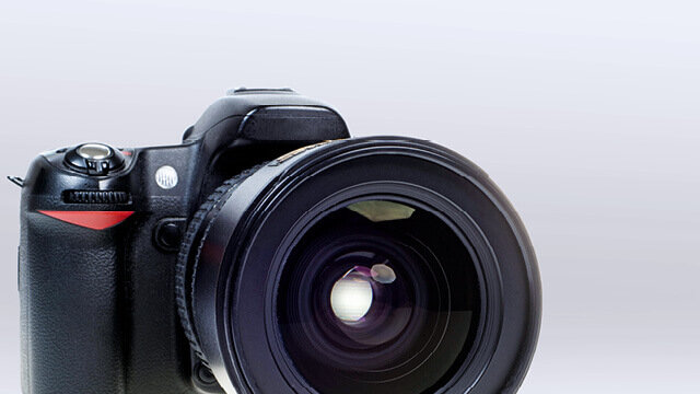 Digitalkamera mit großem Objektiv, fokussiert auf das Objektiv und mit verschwommenem Hintergrund.